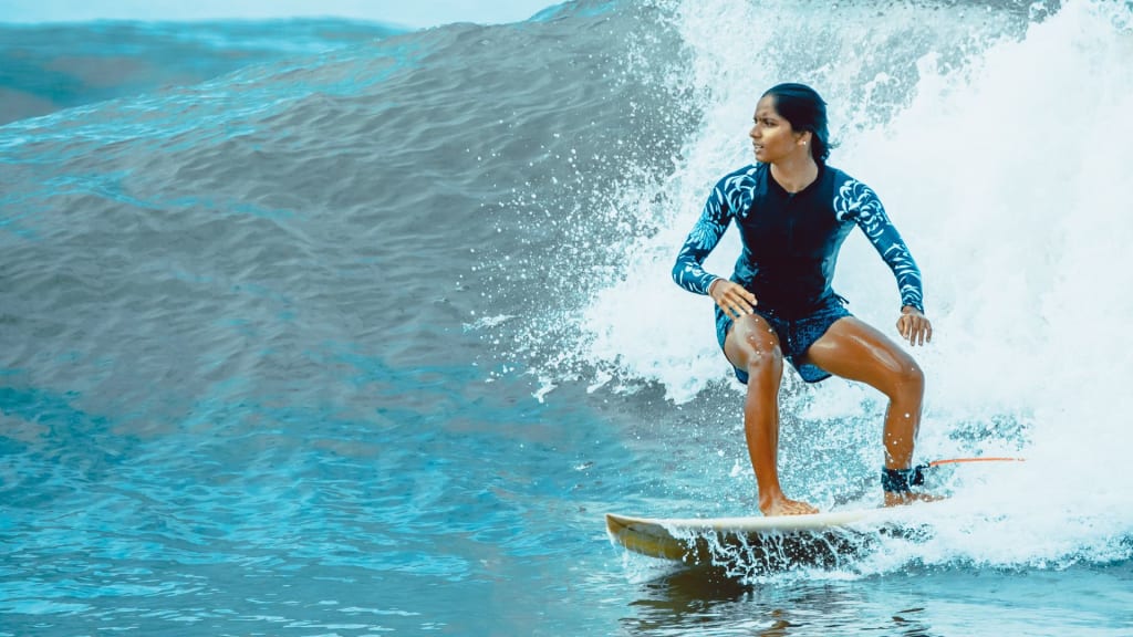 A person in a black and blue wetsuit is surfing on a wave in the ocean.
